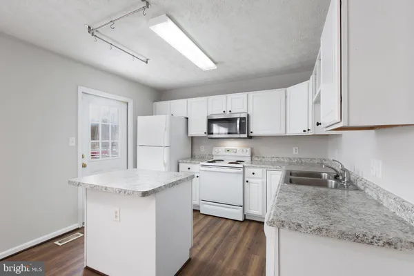a kitchen with white cabinets and white appliances