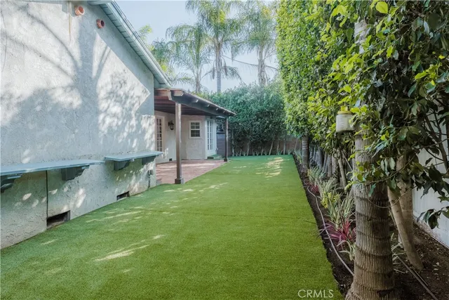 a view of a house with a yard and large trees