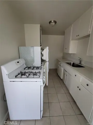 a utility room with a sink a stove and cabinets