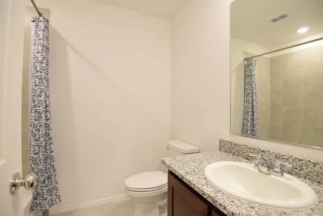 a bathroom with a granite countertop toilet a sink and a mirror