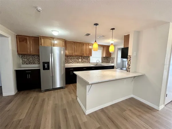 a kitchen with a sink chandelier and wooden floor