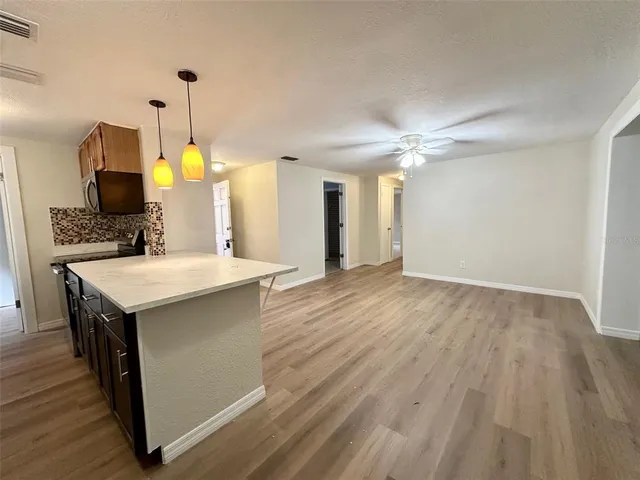 a kitchen with a sink chandelier and wooden floor