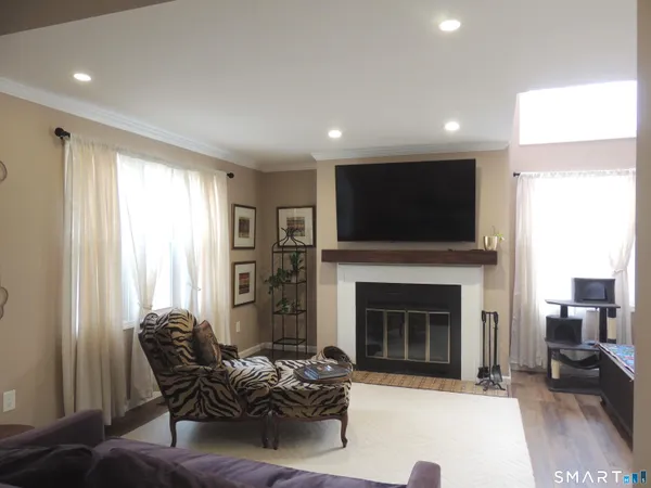 a view of an empty room with wooden floor fireplace and a window
