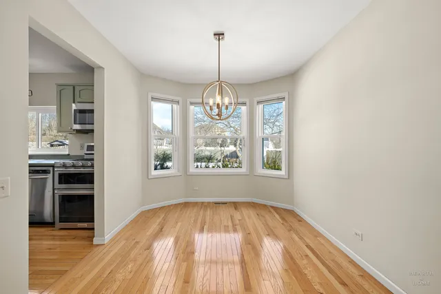a view of empty room with wooden floor and kitchen view