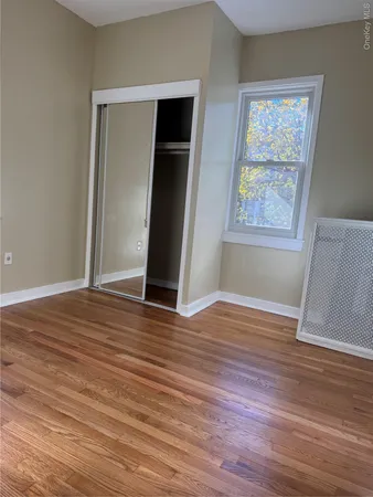 an empty room with wooden floor and window