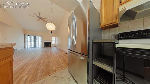 460 Autumn Ridge Circle, Unit D Colorado Springs, CO 80906 - Photo 38 of 38 Kitchen with electric stove, freestanding refrigerator, ceiling fan, a fireplace, and open floor plan