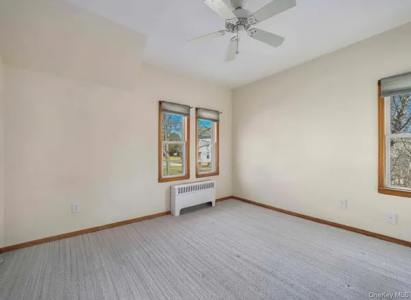 an empty room with wooden floor chandelier fan and windows