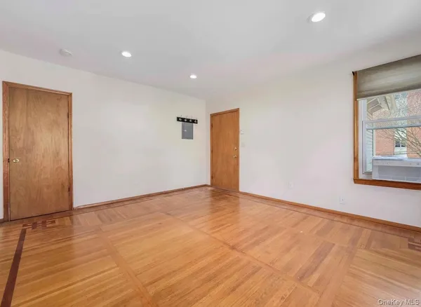 a view of an empty room with wooden floor and a window
