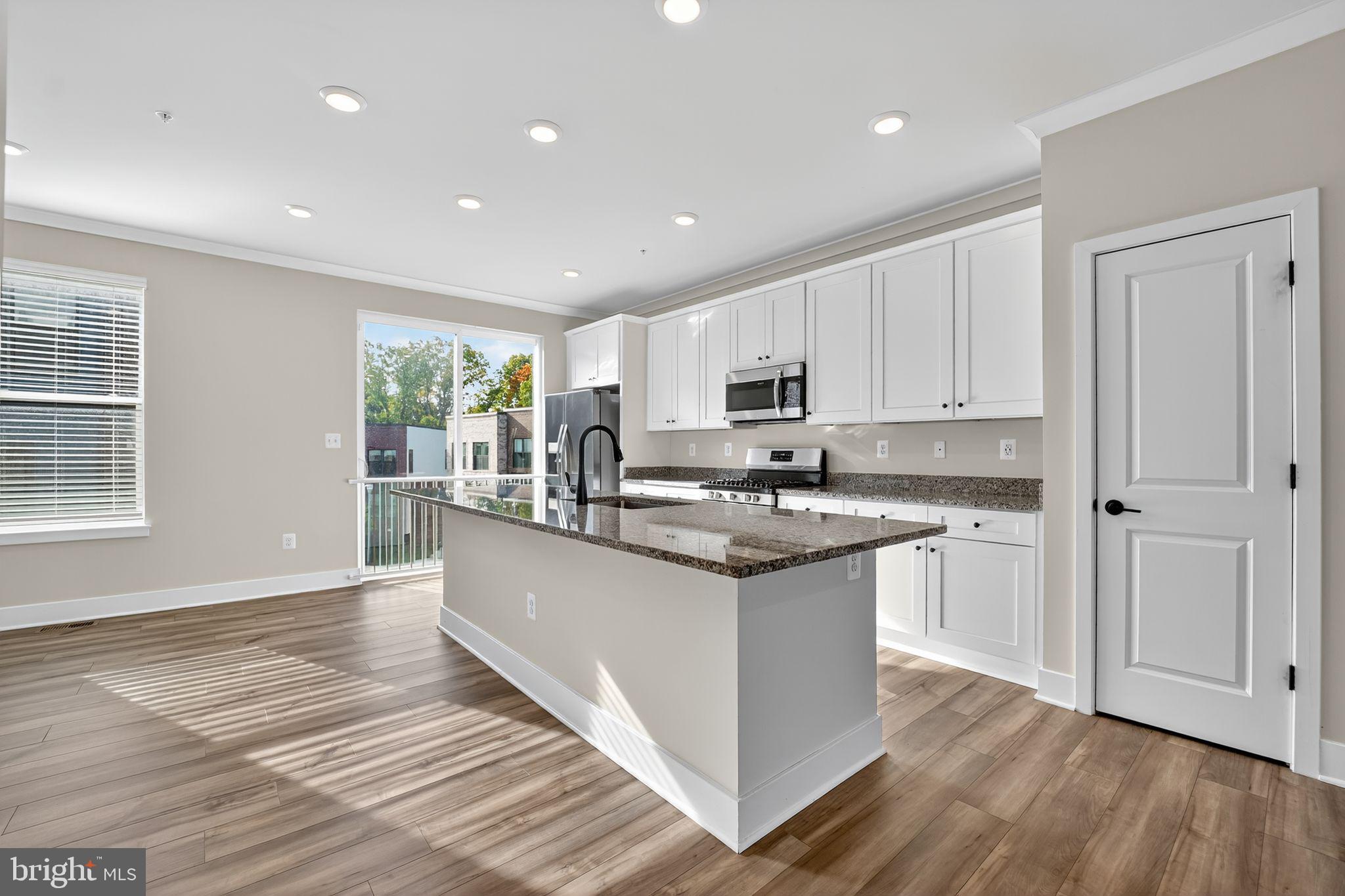 1511 Roland Heights Avenue Baltimore, MD 21211 - Photo 21 of 42 a kitchen with stainless steel appliances granite countertop a stove top oven a sink and white cabinets with wooden floor