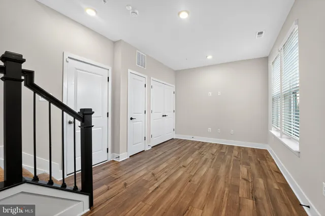 a view of empty room with wooden floor and fan