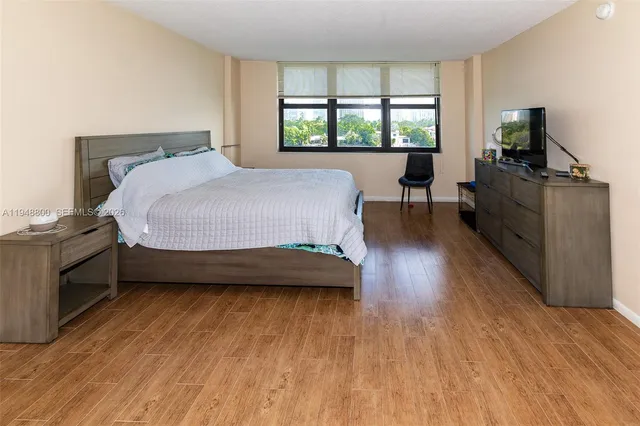 a bedroom with a bed and a flat tv screen on the dresser