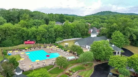 a view of a building with a yard and large trees