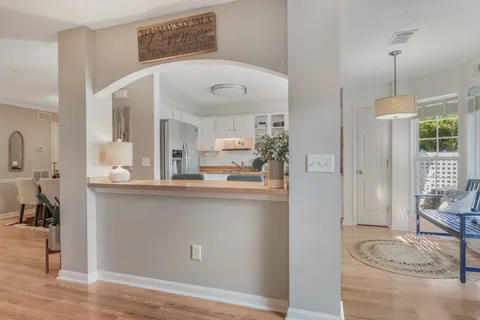a living room with stainless steel appliances kitchen island granite countertop furniture and a wooden floor