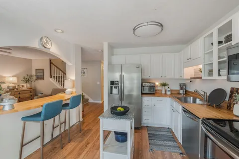 a kitchen with refrigerator and wooden floor