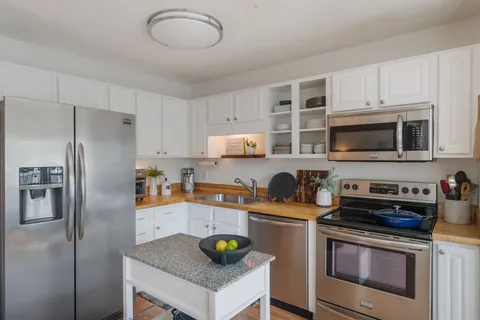 a kitchen with stainless steel appliances a stove a refrigerator a stove a microwave and cabinets