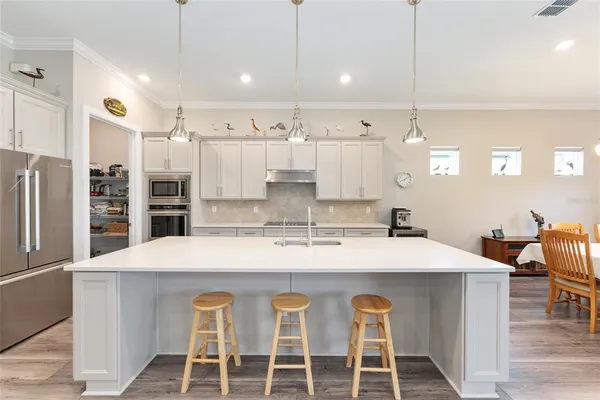 a large white kitchen with kitchen island a sink table and chairs