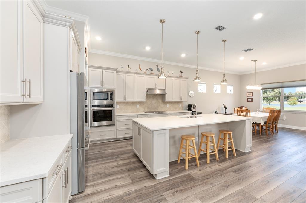 8843 Southwest 57th Pl Road Ocala, FL 34481 - Photo 13 of 64 a large white kitchen with kitchen island a sink table and chairs