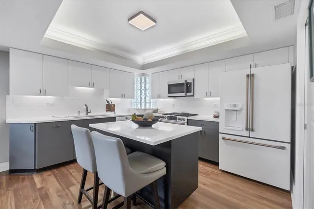 a kitchen with stainless steel appliances a sink a stove a refrigerator cabinets and dining table