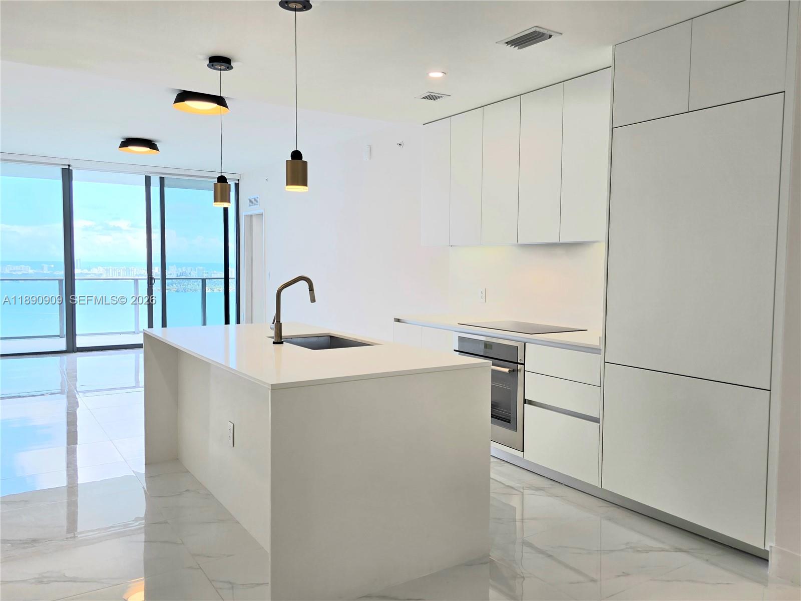 700 Northeast 24th Street, Unit 4004 Miami, FL 33137 - Photo 11 of 68 a kitchen with kitchen island a sink stainless steel appliances and cabinets