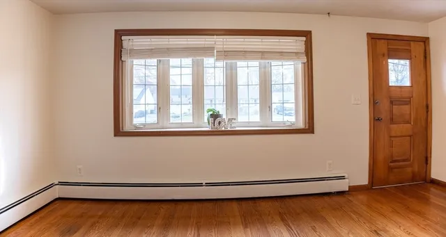 a view of an empty room with wooden floor and a window