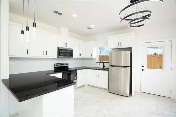a kitchen with stainless steel appliances granite countertop a refrigerator a stove a microwave oven a sink and dishwasher