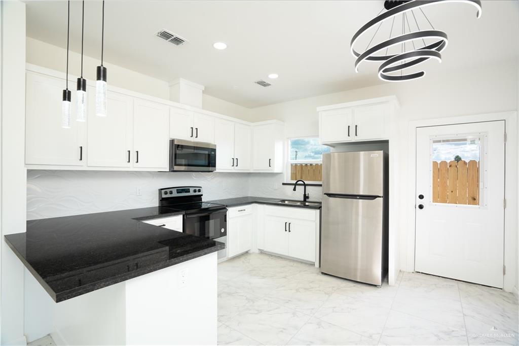 1408 South Xanthia Street, Unit 1 Alton, TX 78573 - Photo 5 of 19 a kitchen with stainless steel appliances granite countertop a refrigerator a stove a microwave oven a sink and dishwasher