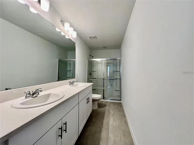 a spacious bathroom with a double vanity sink a mirror and a shower