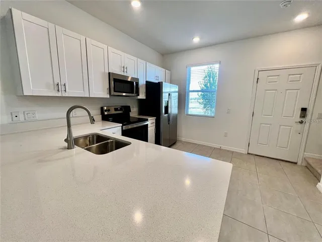 a kitchen with stainless steel appliances granite countertop a sink a stove a microwave and a refrigerator