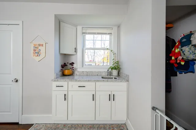 a kitchen with white cabinets and window