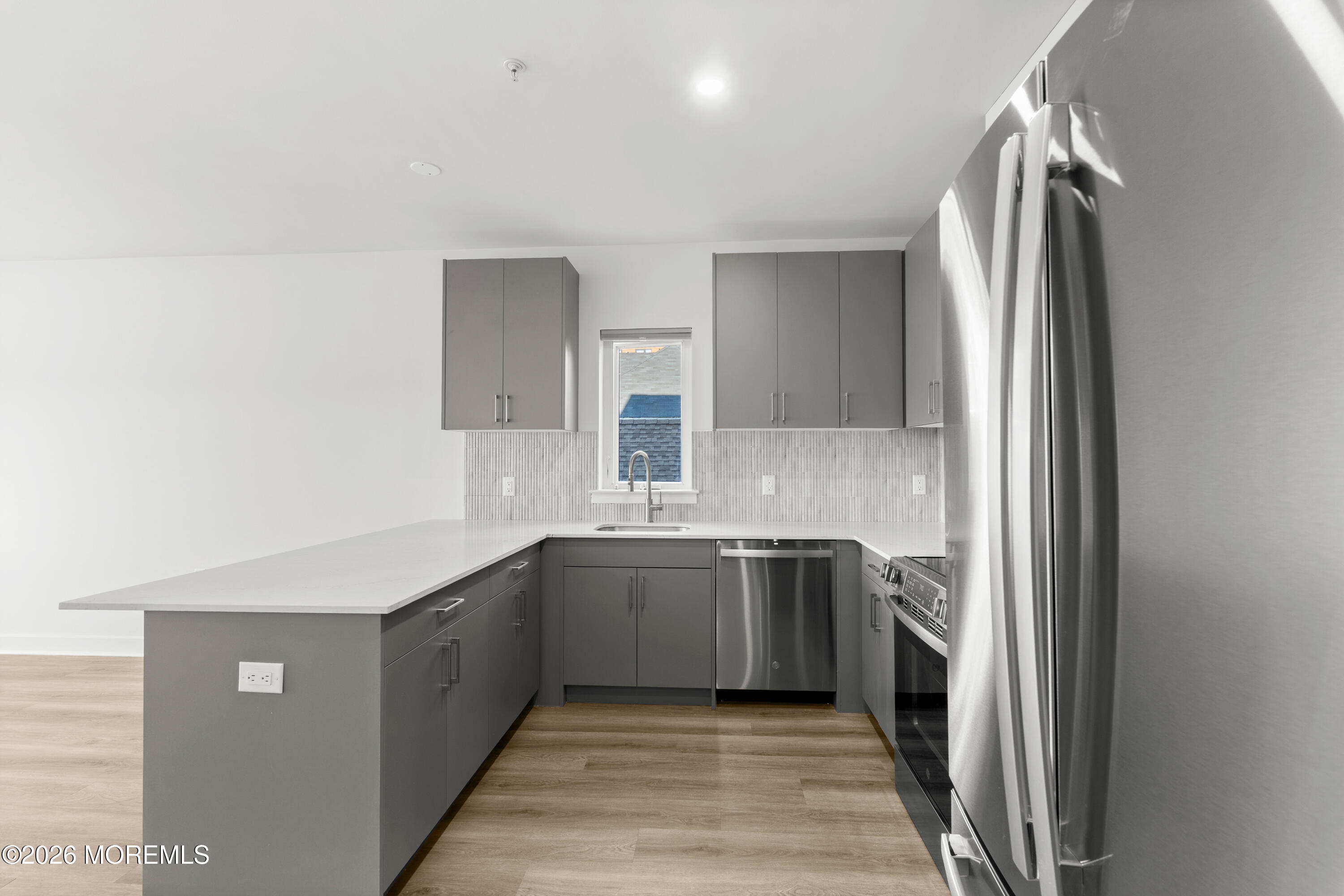 180 Morris Avenue, Unit 101 Long Branch, NJ 07740 - Photo 2 of 9 a large kitchen with a sink and dishwasher a refrigerator with wooden cabinets