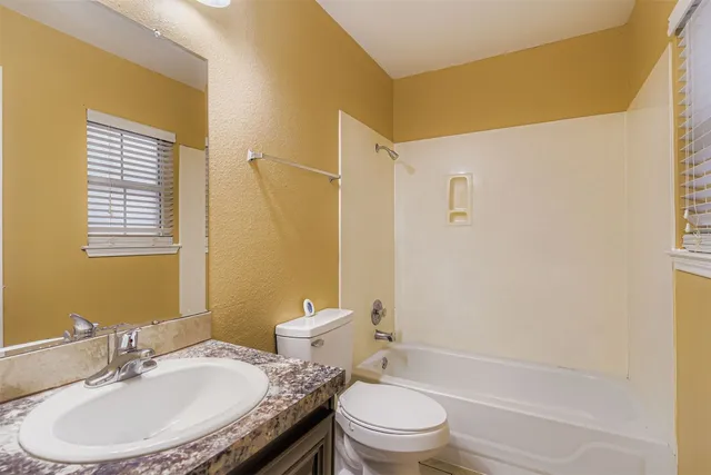 a bathroom with a granite countertop sink toilet a mirror and shower