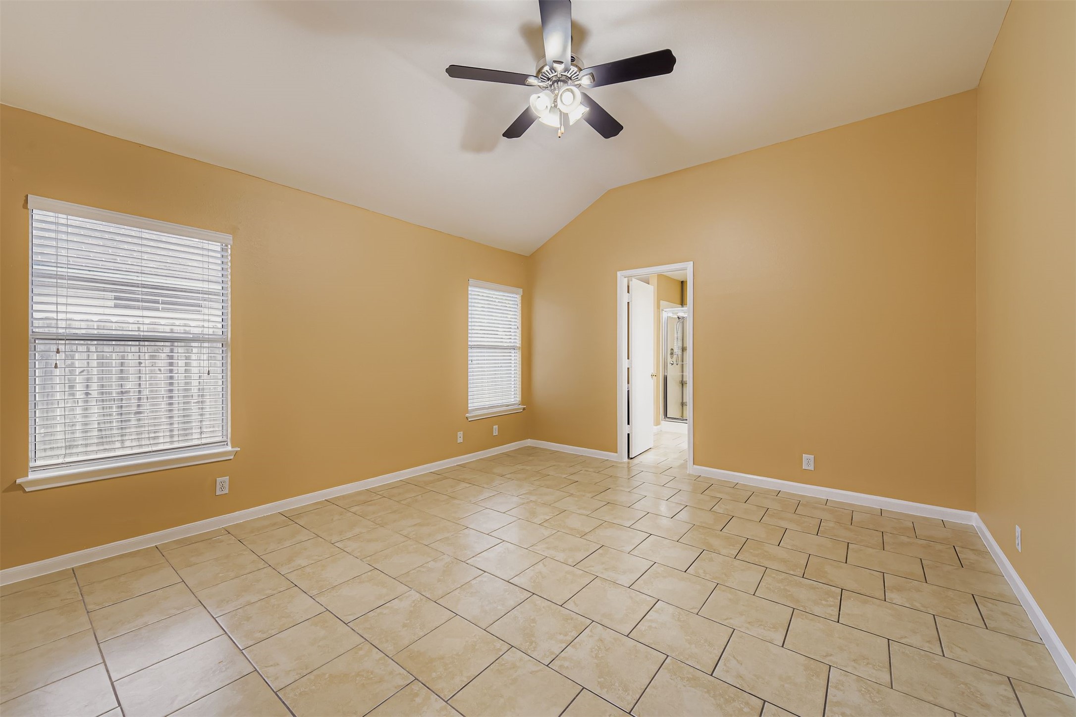 441 Keystone Loop Kyle, TX 78640 - Photo 9 of 17 Primary bedroom featuring vaulted ceiling, light tile patterned floors, and ceiling fan