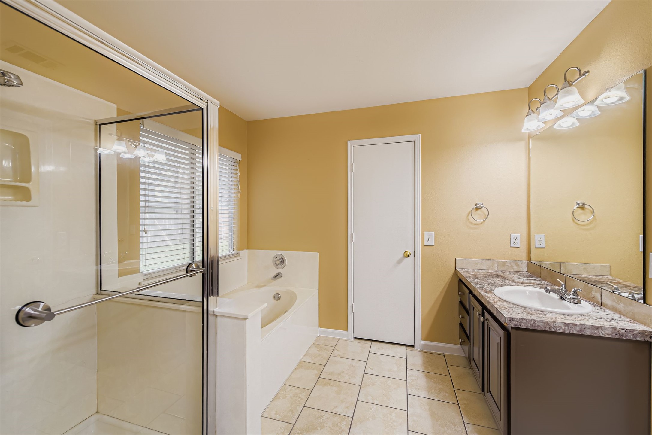 441 Keystone Loop Kyle, TX 78640 - Photo 10 of 17 Primary bathroom featuring two vanities, a stall shower, a bath, and light tile patterned flooring