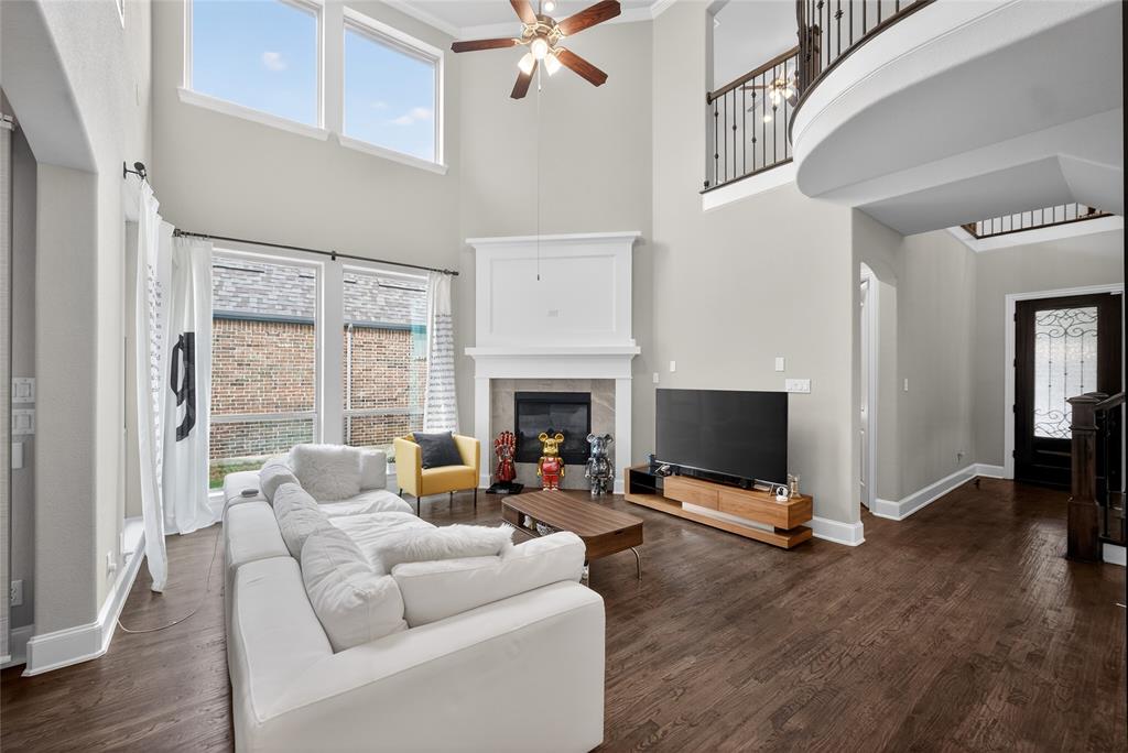 1039 Stephen Street Allen, TX 75013 - Photo 7 of 40 Living area featuring ceiling fan, a glass covered fireplace, dark wood-type flooring, a high ceiling, and ornamental molding