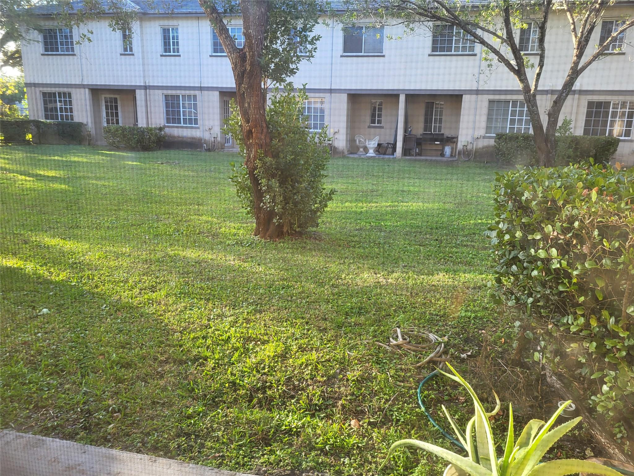 1957 Freeport Drive, Unit 1957 Riviera Beach, FL 33404 - Photo 9 of 14 a view of a brick house next to a yard with plants and trees