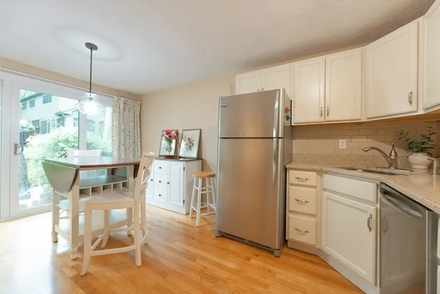 a kitchen with a refrigerator a white cabinets and wooden floor