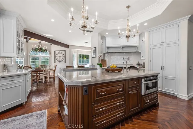 a kitchen with stainless steel appliances granite countertop a stove a refrigerator a sink dishwasher a dining table and chairs with wooden floor