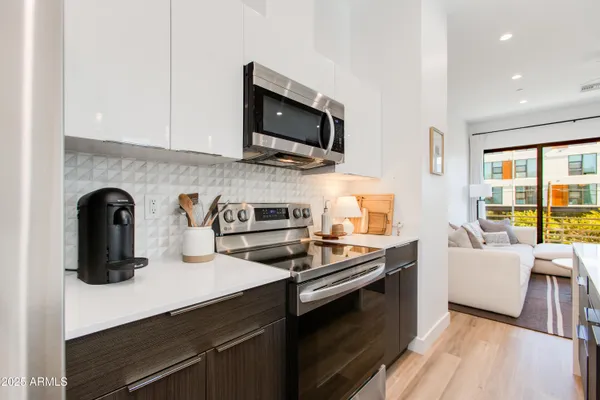 a large white kitchen with sink and stainless steel appliances