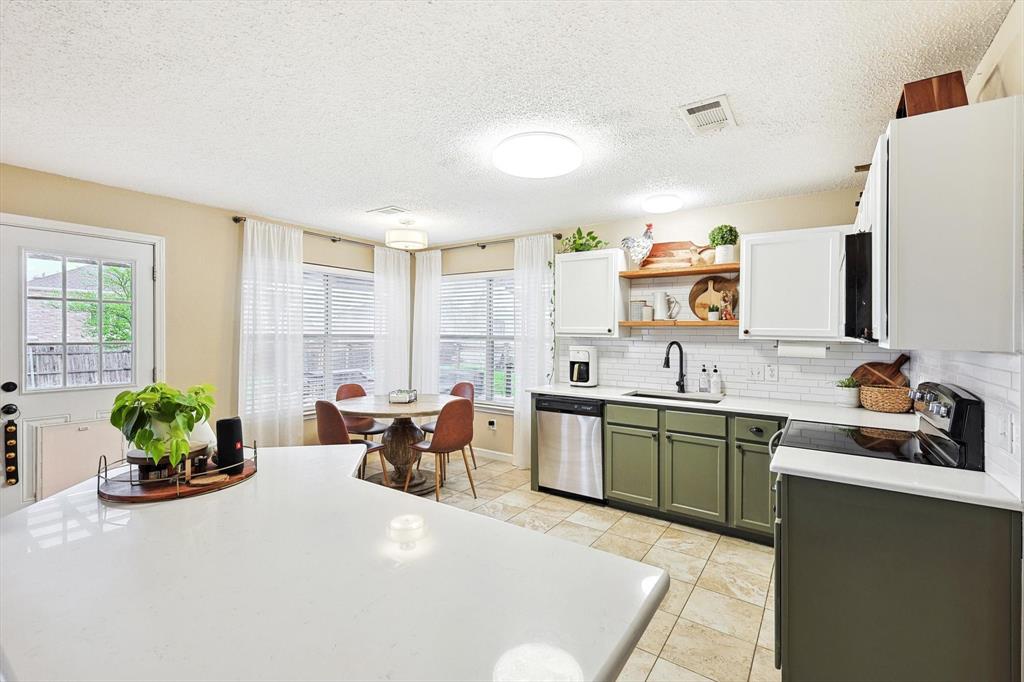1016 Ridgetop Drive Justin, TX 76247 - Photo 12 of 40 Kitchen featuring green cabinetry, a textured ceiling, light countertops, open shelves, and backsplash