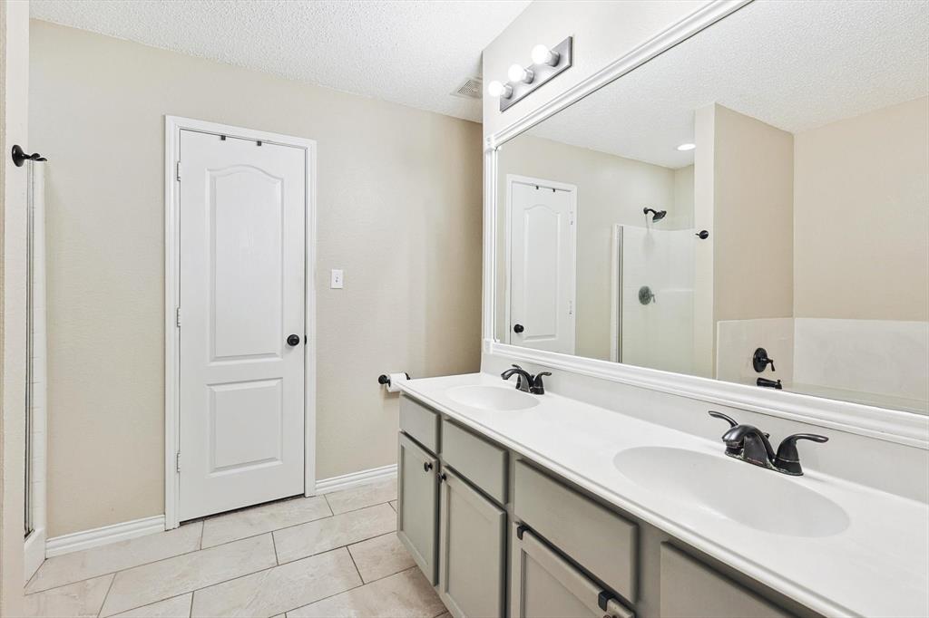 1016 Ridgetop Drive Justin, TX 76247 - Photo 17 of 40 Bathroom featuring a textured ceiling, double vanity, a shower, and tile patterned floors