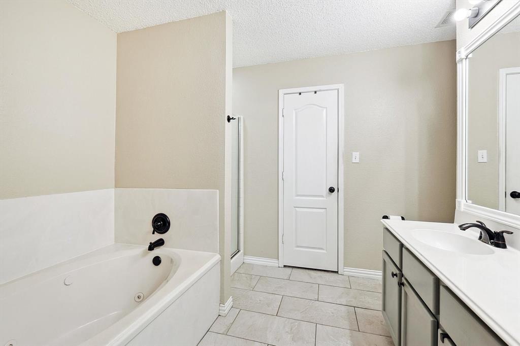 1016 Ridgetop Drive Justin, TX 76247 - Photo 18 of 40 Bathroom featuring vanity, a tub with jets, a textured ceiling, and tile patterned floors