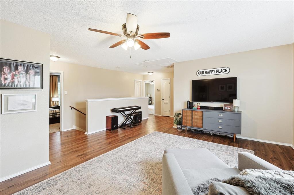 1016 Ridgetop Drive Justin, TX 76247 - Photo 22 of 40 Living area with a textured ceiling, dark wood-style flooring, and a ceiling fan