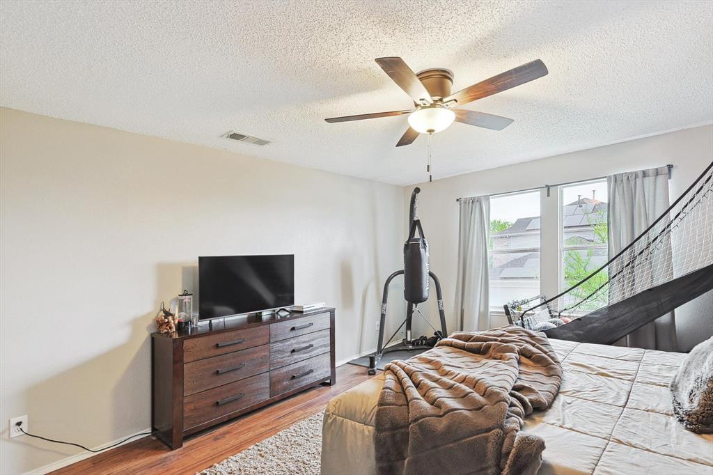 1016 Ridgetop Drive Justin, TX 76247 - Photo 26 of 40 Bedroom with a textured ceiling, light wood-style floors, and a ceiling fan
