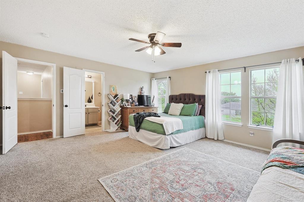 1016 Ridgetop Drive Justin, TX 76247 - Photo 30 of 40 Bedroom featuring light carpet, a textured ceiling, ensuite bath, and a ceiling fan
