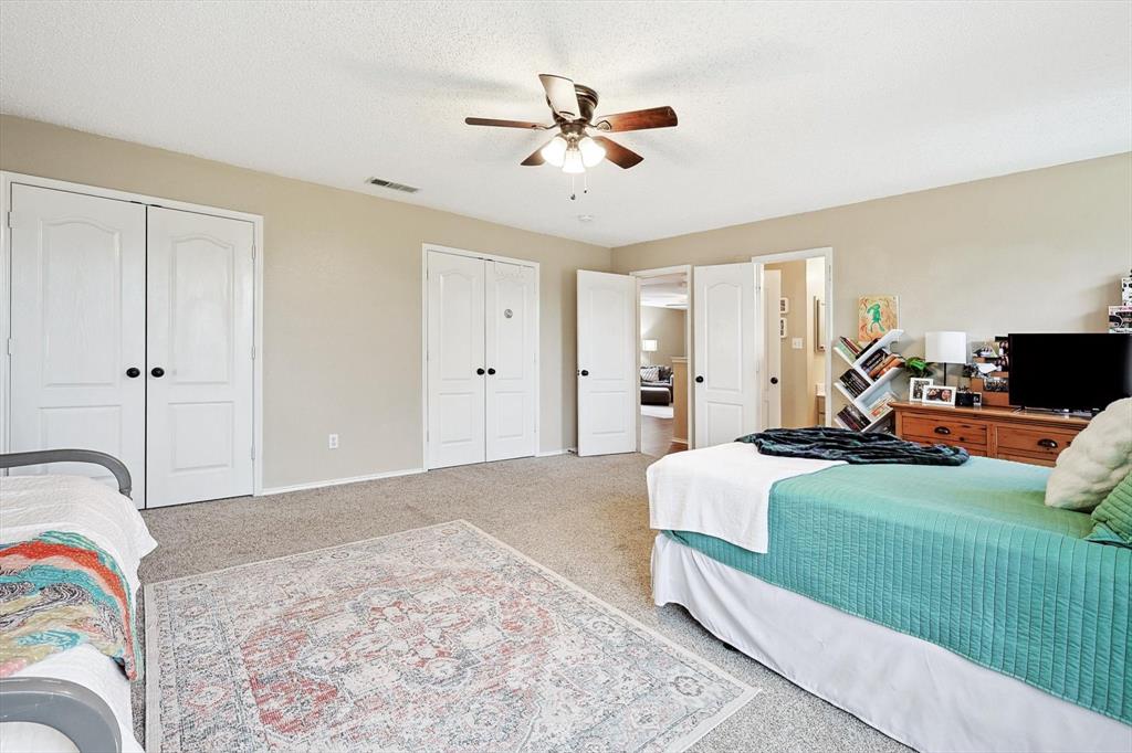 1016 Ridgetop Drive Justin, TX 76247 - Photo 31 of 40 Bedroom with two closets, carpet floors, a textured ceiling, and a ceiling fan