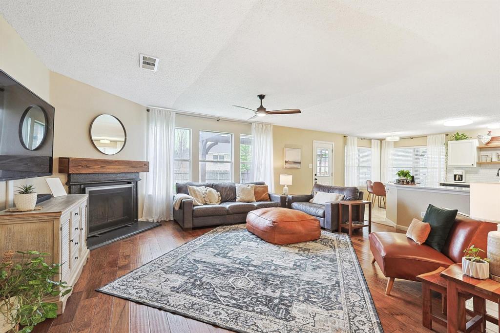 1016 Ridgetop Drive Justin, TX 76247 - Photo 7 of 40 Living room with a fireplace with raised hearth, a textured ceiling, hardwood / wood-style floors, and a ceiling fan