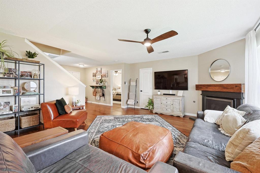 1016 Ridgetop Drive Justin, TX 76247 - Photo 10 of 40 Living area with wood finished floors, a fireplace, ceiling fan, and a textured ceiling