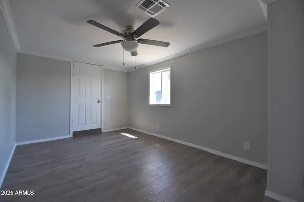 an empty room with wooden floor ceiling fan and windows