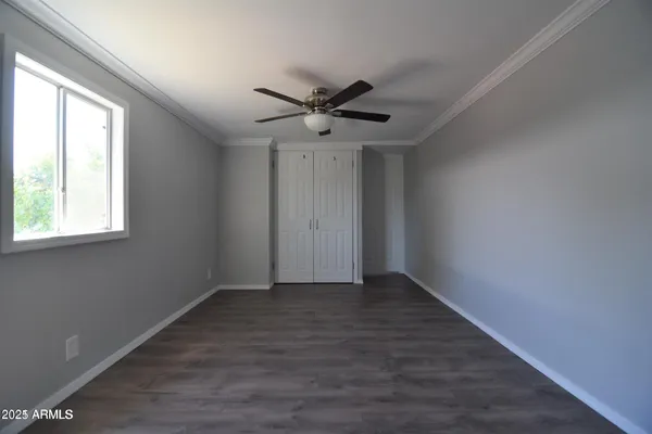 an empty room with wooden floor ceiling fan and windows