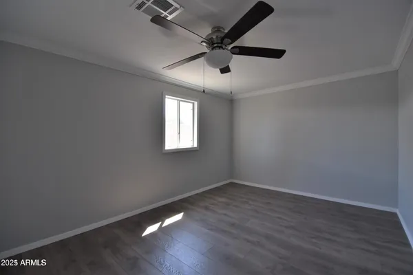 an empty room with wooden floor ceiling fan and windows